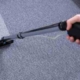 man professionally cleaning a carpet with a wand