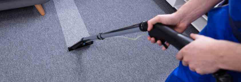 man professionally cleaning a carpet with a wand