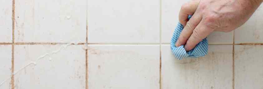 person cleaning bathroom tile